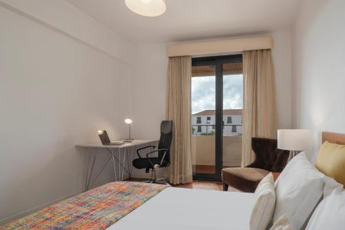 a hotel room with a bed and a desk and a window at Casa Sta Clara by An Island Apart in Funchal