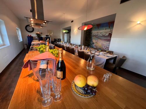a long wooden table with wine bottles and fruit on it at Large villa for 20 guests on large estate with private pool and tennis court Big conference room with facilities VILLAITALY EU in Cairo Montenotte