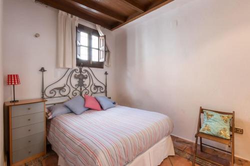 a bedroom with a bed and a dresser and a window at LA ROCHINA in Granada