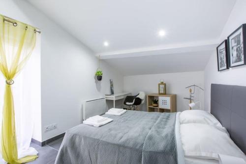 a white bedroom with a bed and a window at Agréable et moderne 2 pièces ~ confort et design in Clermont-Ferrand