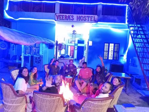 Veera's Hostel في بوشكار: مجموعة من الناس يجلسون في كراسي حول النار