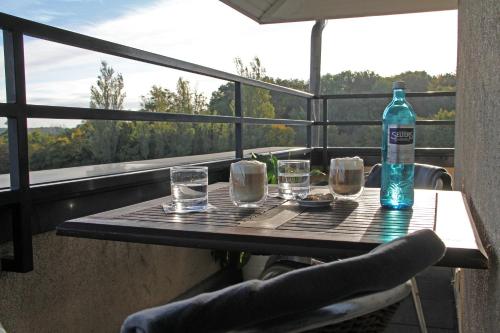 a table with glasses and a bottle of water on a balcony at City Hotel Frankfurt Bad Vilbel in Bad Vilbel