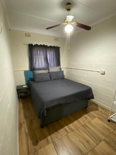sypialnia z łóżkiem i wentylatorem sufitowym w obiekcie Dickens Garden Flat w mieście Empangeni