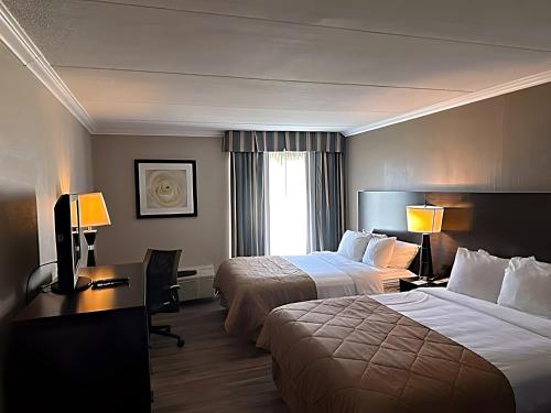 una camera d'albergo con due letti e una scrivania con due lampade di Suburban Studios Syracuse Fairgrounds a Syracuse