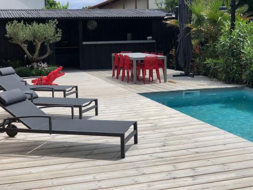a patio with a table and chairs next to a pool at Nanie - Villa centre-ville, piscine, wifi - La Teste de Buch in La Teste-de-Buch