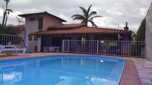 a blue swimming pool in front of a house at Casa Beira Lago in Capitólio