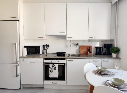 a kitchen with white cabinets and a table and a stove at Beautiful studio in the heart of Lahti in Lahti