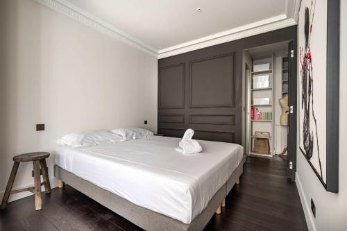 - une chambre avec un grand lit blanc et un tabouret dans l'établissement Studio de l'Horloge - Welkeys, à Antibes