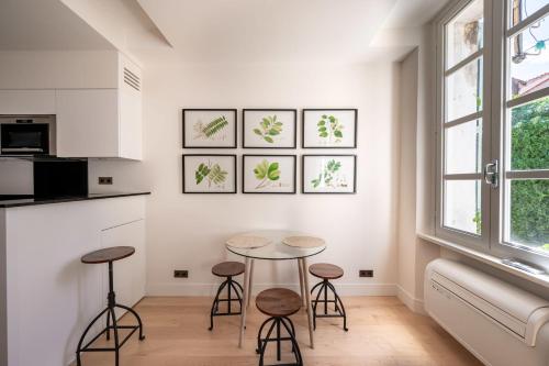 - une cuisine avec deux tables et des tabourets dans une pièce dans l'établissement Studio de l'Horloge - Welkeys, à Antibes