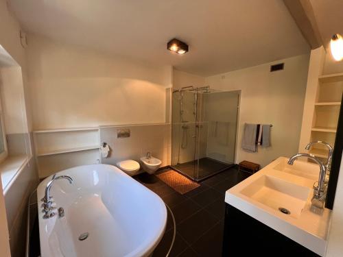 a bathroom with a tub and a shower and a sink at Large villa for 20 guests on large estate with private pool and tennis court Big conference room with facilities VILLAITALY EU in Cairo Montenotte