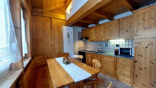uma cozinha com armários de madeira e uma mesa de madeira em Appartamento Fiocco Di Neve em Campitello di Fassa