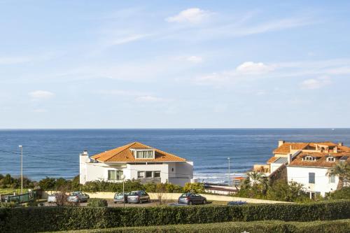 une maison avec des voitures garées en face de l'océan dans l'établissement Studio des Falaises - Welkeys, à Anglet