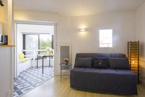 un salon avec un canapé bleu et une cuisine dans l'établissement Studio des Falaises - Welkeys, à Anglet