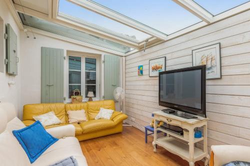 een woonkamer met een gele bank en een flatscreen-tv bij Nice studio with veranda nearby the beach in La Flotte - Welkeys in La Flotte