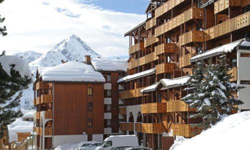un edificio con nieve en el suelo junto a un aparcamiento en Les deux Alpes : charmant studio, quartier Vénosc en Les Deux Alpes