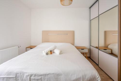 une chambre avec un lit blanc avec deux serviettes dessus dans l'établissement Appartement Veil - Welkeys, à Clichy