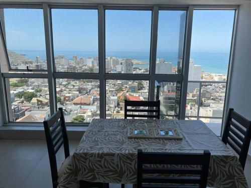 Moderno Depto con Vista al Mar في كومودورو ريفادافيا: غرفة طعام مع طاولة وكراسي أمام النافذة
