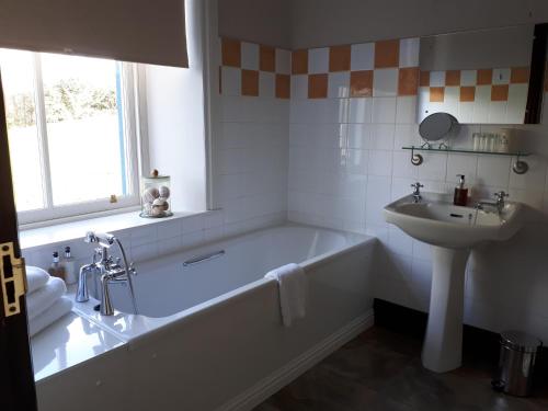 Baño blanco con bañera y lavamanos en Corsewall Arms Guest House, en Stranraer