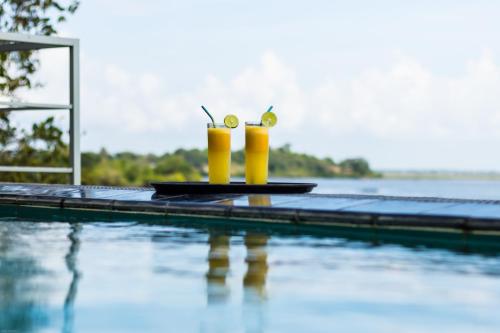 una piscina con dos bebidas en una mesa junto al agua en Oruwa Boutique Villas, en Arugam Bay