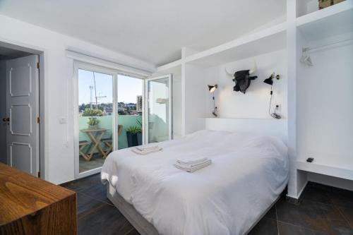 a white bedroom with a bed and a balcony at Casa Estábulo- Cozy Rustic Farmhouse LOFT TOURO in Estômbar