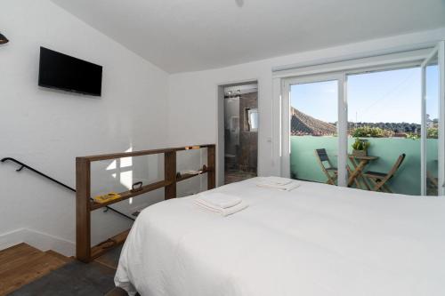 a white bedroom with a bed and a balcony at Casa Estábulo- Cozy Rustic Farmhouse LOFT TOURO in Estômbar