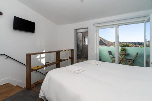 een witte slaapkamer met een bed en een balkon bij Casa Estábulo- Cozy Rustic Farmhouse LOFT TOURO in Estômbar