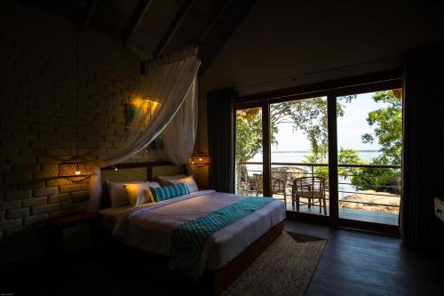 a bedroom with a bed and a large window at Oruwa Boutique Villas in Arugam Bay