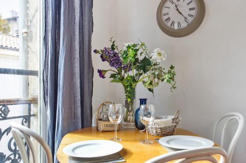 une table à manger avec un vase de fleurs et une horloge dans l'établissement Superb flat nearby the Old Port at the heart of Marseille - Welkeys, à Marseille