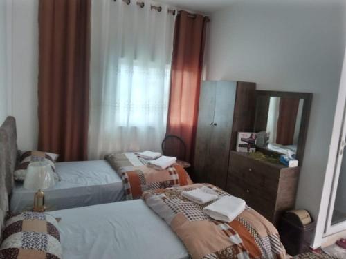 a bedroom with two beds and a dresser and a mirror at Its your choice hostel in Wadi Musa