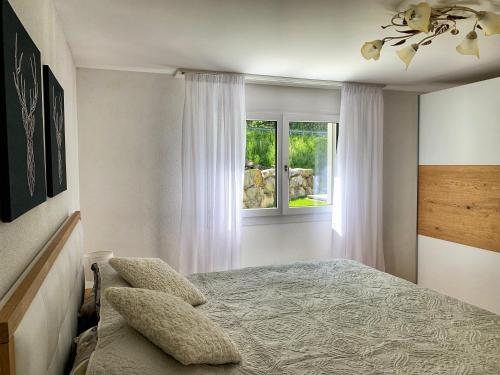 a bedroom with a bed and a window at Büelbad - Relax Holiday Apartment in Kandersteg