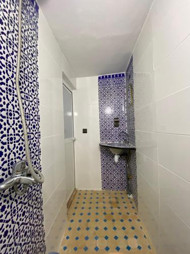 een badkamer met blauwe en witte tegels en een douche bij Dar benelmahi in Fès