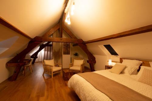 ein Schlafzimmer mit einem Bett und Stühlen im Dachgeschoss in der Unterkunft La Ferme du P'tit Colibri in Gury