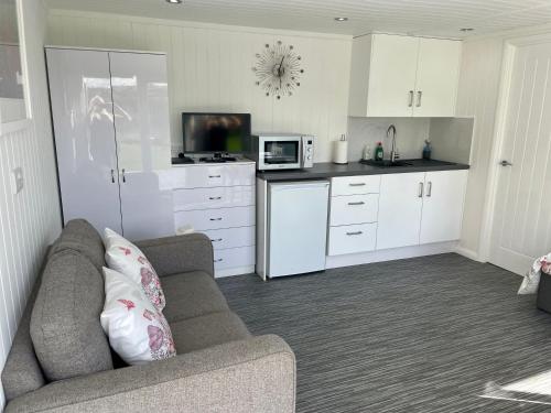 ein Wohnzimmer mit Couch und Küche in der Unterkunft The Garden Room - A cosy country stay in Cornwall in Callington