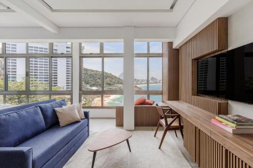 a living room with a blue couch and a large window at Beach Loft next to the Sheraton Leblon in Rio de Janeiro