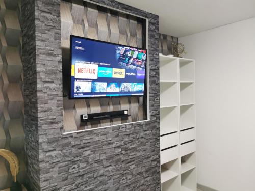 a television on a brick wall in a living room at L'AisCal Appart-Hôtel 6 Personnes in Calais
