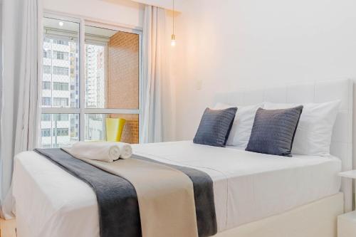 a bedroom with a large white bed with a window at BR07 Apto 2/4 a 550m da Praia Porto da Barra in Salvador