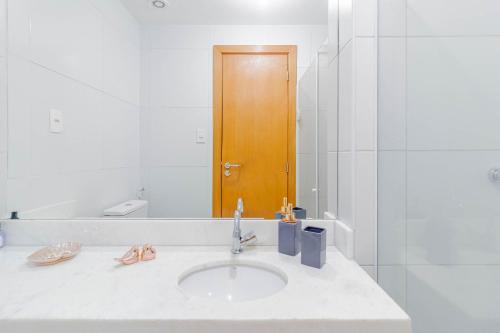 a bathroom with a sink and a wooden door at BR07 Apto 2/4 a 550m da Praia Porto da Barra in Salvador