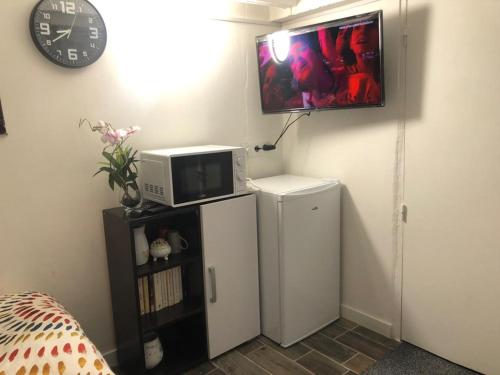 a room with a microwave on top of a refrigerator at Studio individuel près de Paris in Mantes-la-Jolie