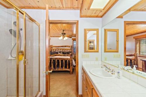 a bathroom with a sink and a shower and a bed at CUSTOM SINGLE STORY CABIN WITH JACUZZI POOL TABLE & BIG GAME ROOM WITH ARCADE games in Big Bear Lake