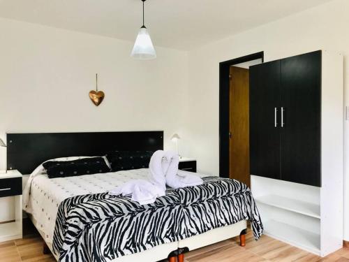 a bedroom with a black and white bed with towels on it at LA MILAGROS PIQUITO DE ORO in Merlo