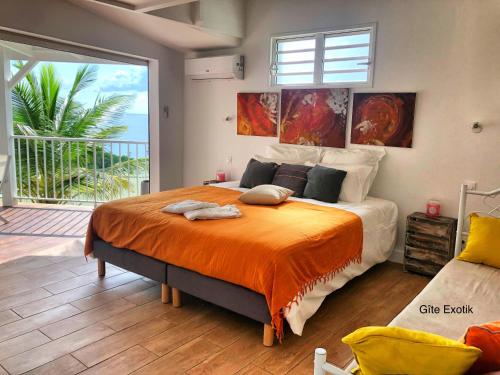 a bedroom with a large bed with an orange blanket at Residence O Coeur de Deshaies Appartements Exotik et Tropikal in Deshaies
