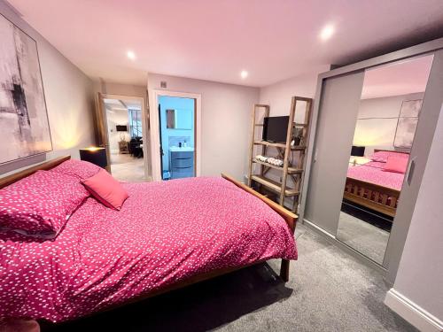 een slaapkamer met een roze bed en een spiegel bij Oliva Verde in Cromer