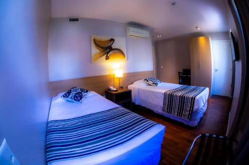 a hotel room with two beds and a lamp at Hotel Nacional Inn Porto Alegre - Estamos abertos - 200 metros do Complexo Hospitalar Santa Casa in Porto Alegre