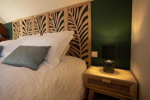 a bedroom with a white bed with a wooden headboard at La Ferme du P'tit Colibri in Gury