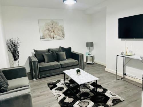 a living room with a couch and a table at Beautiful and Homely 3 Bed House With FREE Parking So Close To Man City and City Centre in Manchester