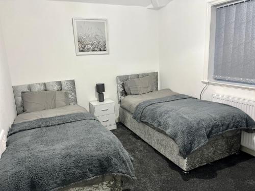 1 dormitorio con 2 camas y ventana en Beautiful and Homely 3 Bed House With FREE Parking So Close To Man City and City Centre en Mánchester