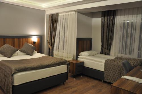 um quarto de hotel com duas camas e uma secretária em ERZURUM DAMAK GRUP em Erzurum