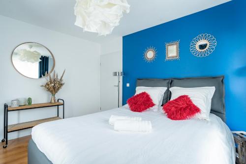 Dormitorio azul con cama blanca y almohadas rojas en Le vintage - Wifi - Parking gratuit, en Monswiller