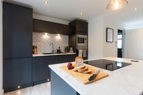 a kitchen with black cabinets and a cutting board on a counter at Stunning Pet-Friendly Home with Hot Tub less than one minute walk from Barmouth Beach in Barmouth
