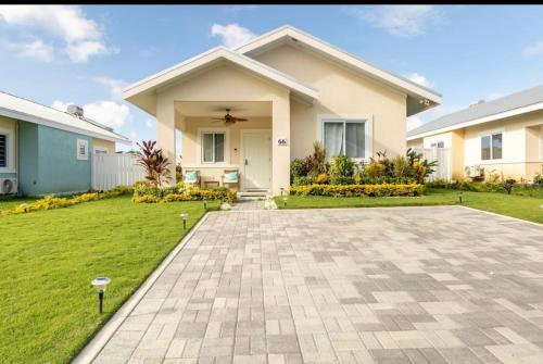 a house with a grass yard and a driveway at Natty’s Cozy Beach house in Hanover Jamaica in Point